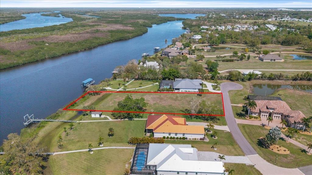 An aerial view shows a rectangular vacant lot bordered by a river and residential homes — 2009 TREASURE LANE, PUNTA GORDA, FL