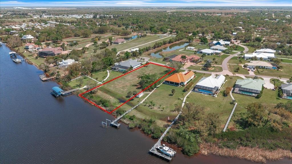 An aerial view shows a vacant waterfront lot outlined in red next to residential homes — 2009 TREASURE LANE, PUNTA GORDA, FL