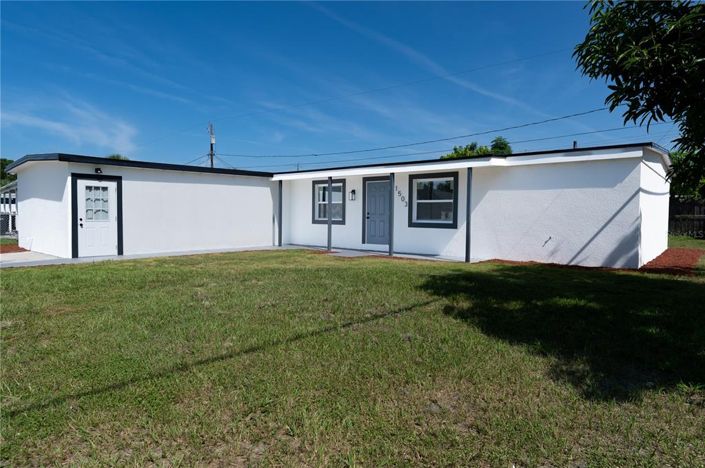 A white single-story house with a flat roof, dark trim, and a front entrance — 1503 LANCELOT LOOP, TAMPA, FL