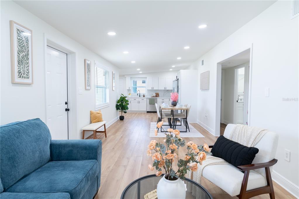 An open-concept living and dining area features white cabinetry, light wood flooring, and recessed lighting — 1503 LANCELOT LOOP, TAMPA, FL