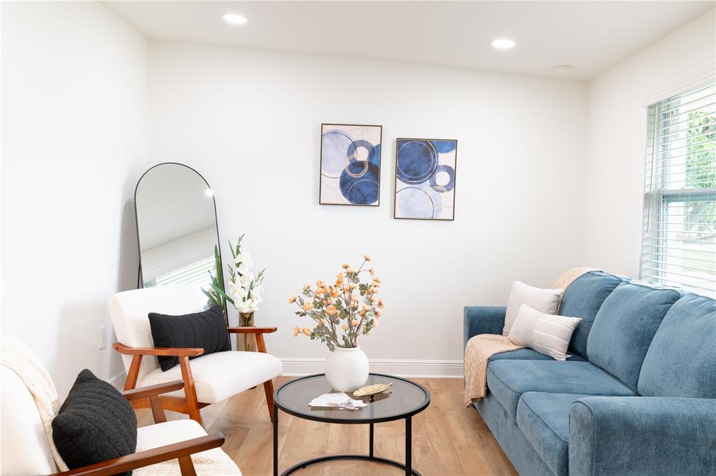 A living room features a blue sofa, two white armchairs, a coffee table, and wall art — 1503 LANCELOT LOOP, TAMPA, FL