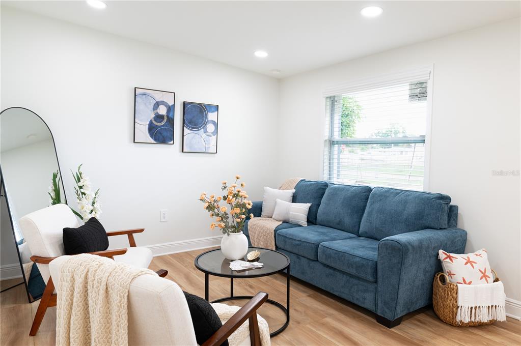 A living room features a blue sofa, two white armchairs, and a round coffee table — 1503 LANCELOT LOOP, TAMPA, FL