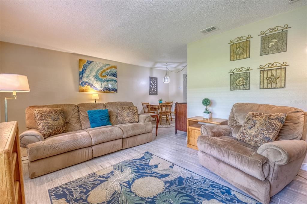 A living room with beige furniture, a blue patterned rug, and light-colored tile flooring — 10039 62ND AVENUE N UNIT 2, ST PETERSBURG, FL