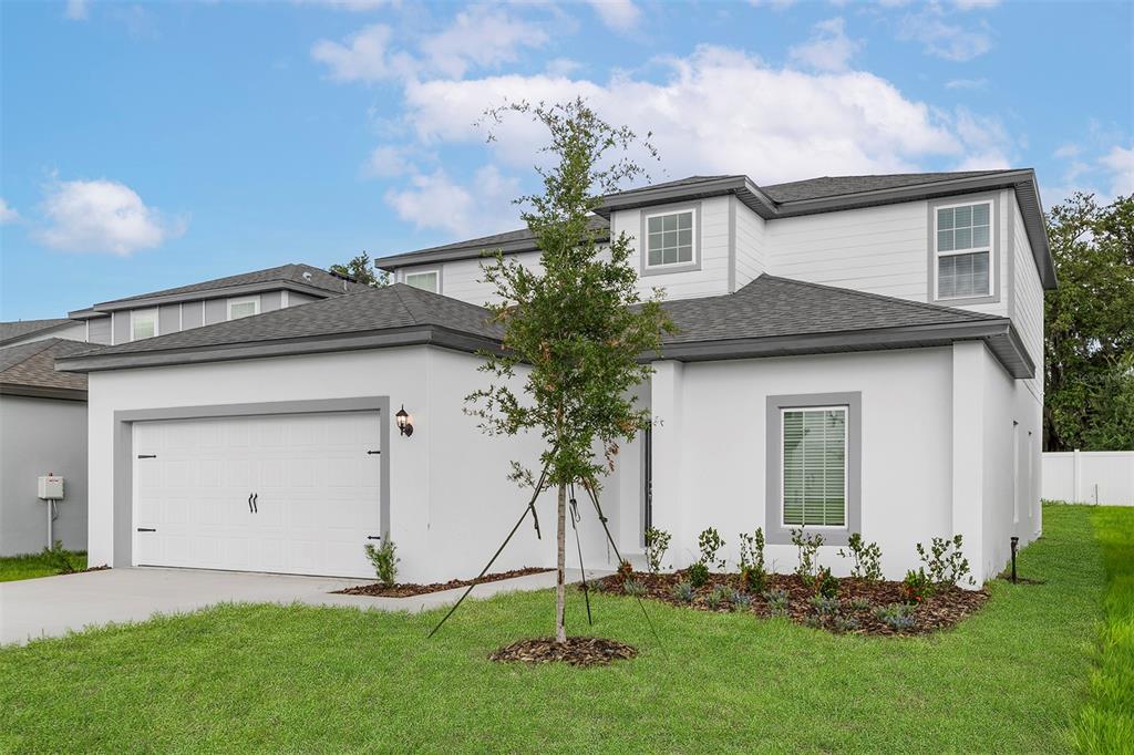 A two-story white house with a gray roof, a garage, and a small front yard — 13347 TULA LOOP, ASTATULA, FL