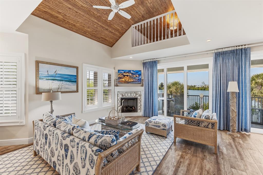 A living room features a vaulted wood ceiling, a shell-covered fireplace, and water views — 40 SEAWATCH LAKE DRIVE, BOCA GRANDE, FL