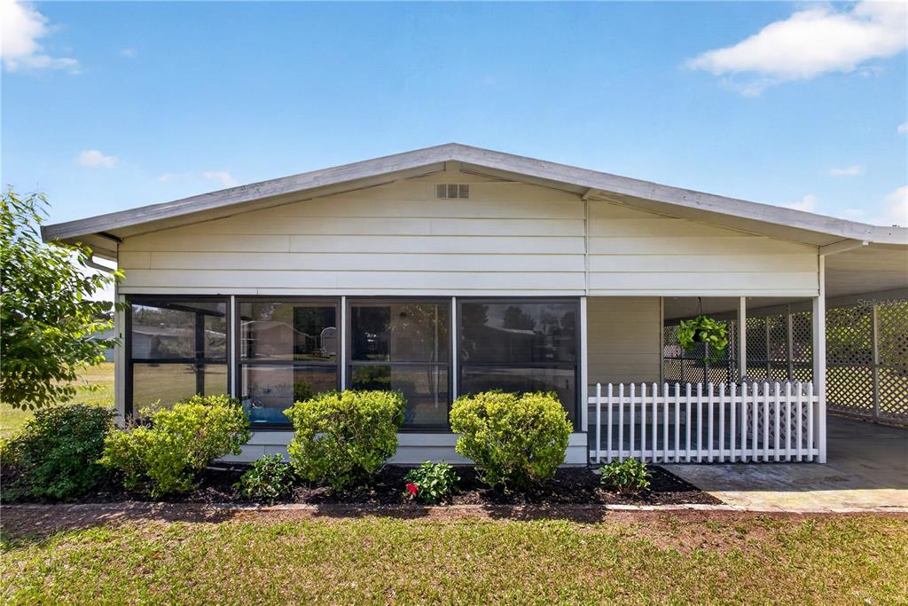 A single-story home features a screened-in porch, a white picket fence, and an attached carport — 8972 SW 103RD LANE, OCALA, FL