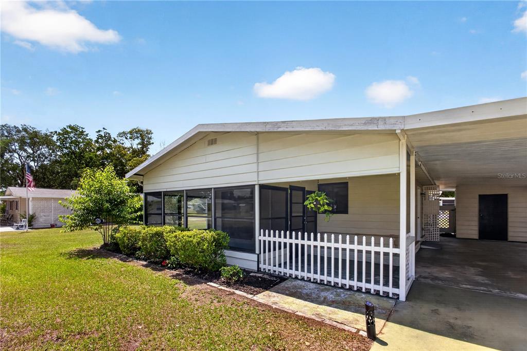 A single-story house with white siding and a screened-in porch sits on a grassy lot — 8972 SW 103RD LANE, OCALA, FL