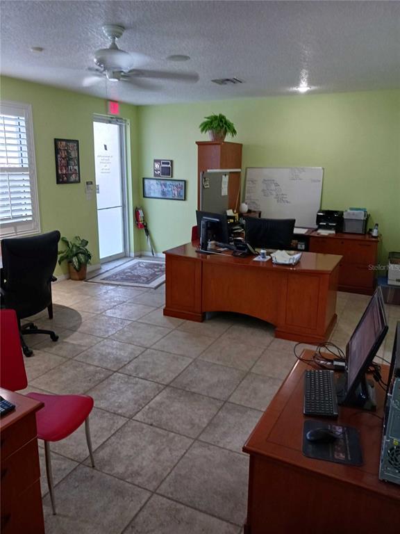 An office space features a wooden desk, tile flooring, a ceiling fan, and light green walls — 515 27TH STREET E UNIT 7, BRADENTON, FL