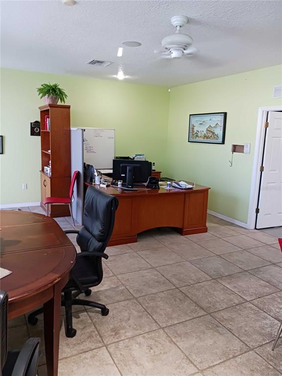 An office space features a wooden desk, a black office chair, and light green walls — 515 27TH STREET E UNIT 7, BRADENTON, FL