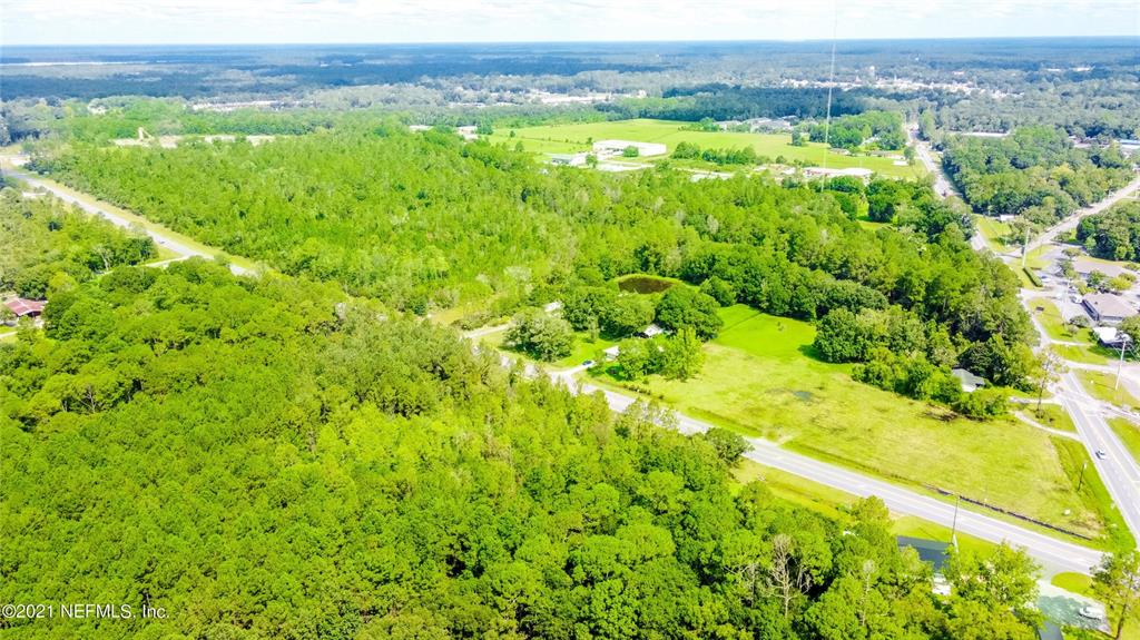 An aerial view shows a large, wooded plot of land adjacent to a paved road — 10422 SE SR 100, STARKE, FL