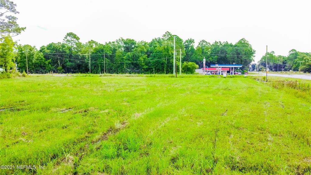 A wide, grassy vacant lot sits in front of a line of trees and a gas station — 10422 SE SR 100, STARKE, FL