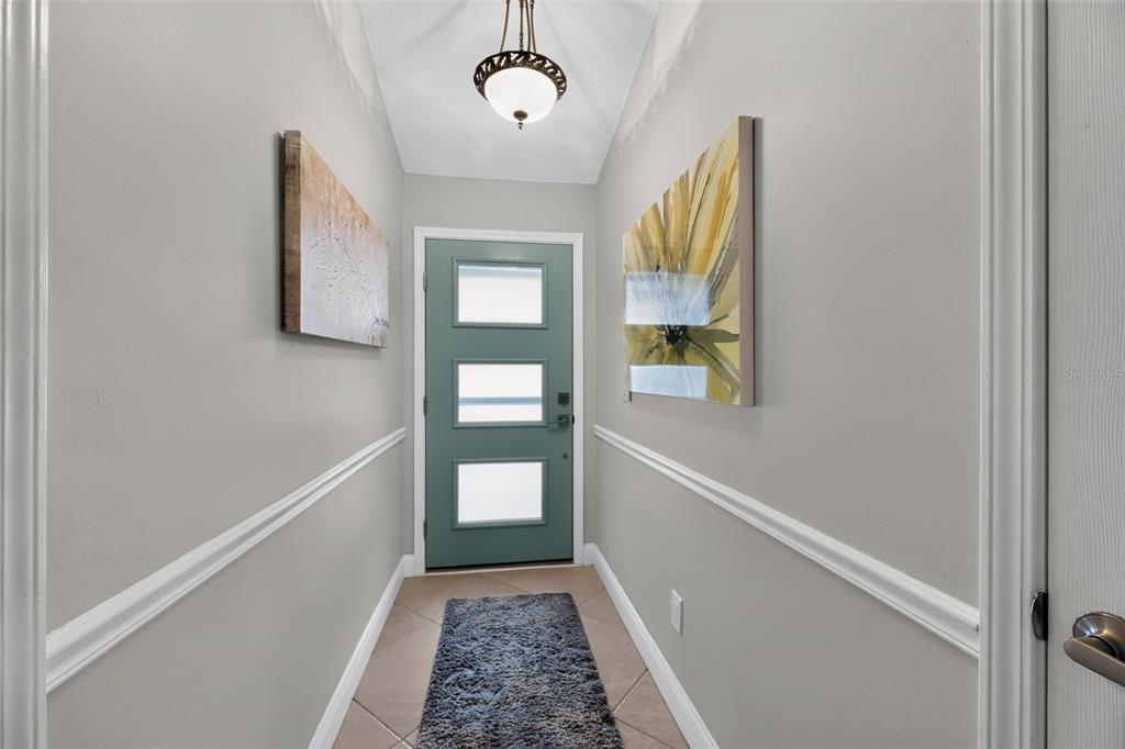 A narrow entryway features a teal front door with three glass panels and gray walls — 590 ASHCROFT LANDING DRIVE, JACKSONVILLE, FL