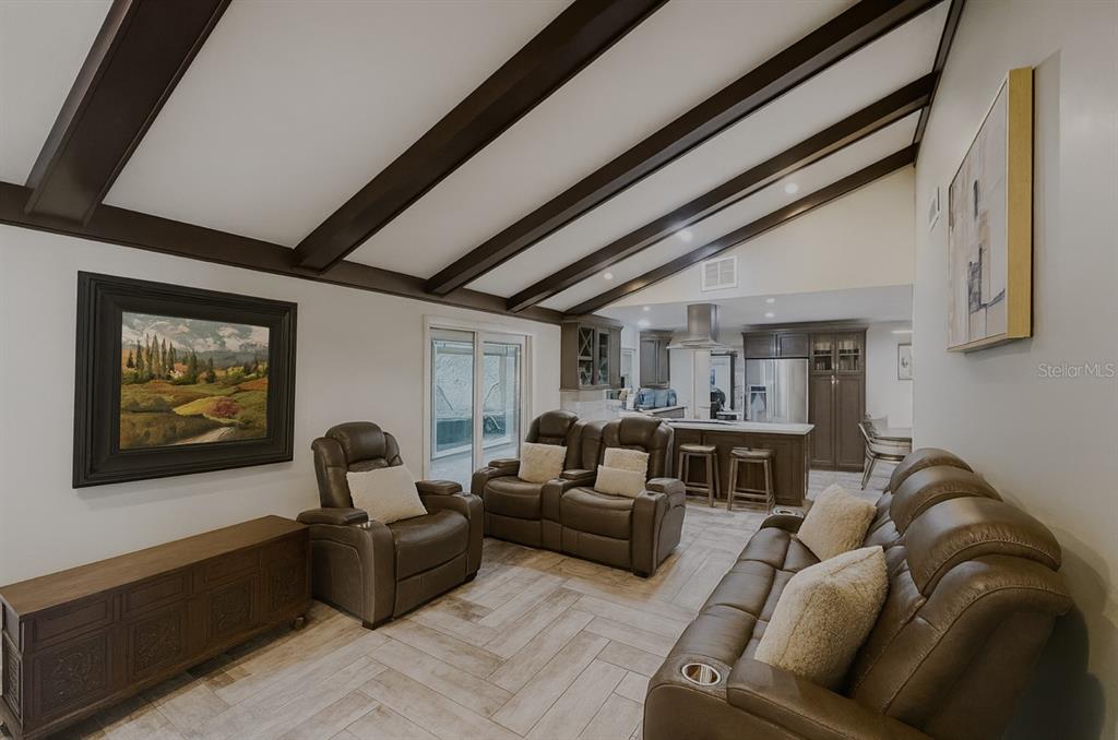 A living room with vaulted ceilings, exposed beams, and brown leather furniture on tiled floors — 414 TIMBERCOVE CIRCLE, LONGWOOD, FL