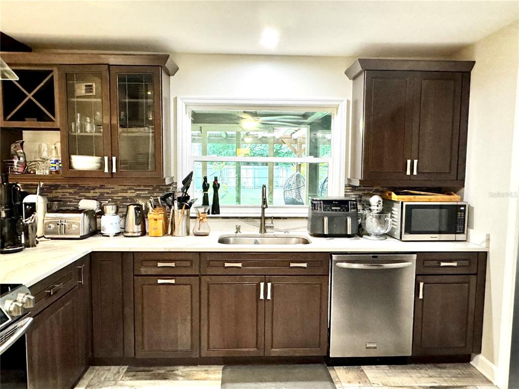 A kitchen features dark wood cabinets, stainless steel appliances, a window, and a tiled backsplash — 414 TIMBERCOVE CIRCLE, LONGWOOD, FL