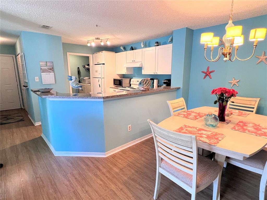 A dining room features a light-colored table, four chairs, and blue walls with starfish decor — 4040 CROCKERS LAKE BOULEVARD UNIT 1717, SARASOTA, FL