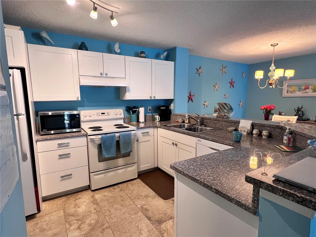 A living room features light blue walls, a striped sofa, a matching ottoman, and sliding doors — 4040 CROCKERS LAKE BOULEVARD UNIT 1717, SARASOTA, FL