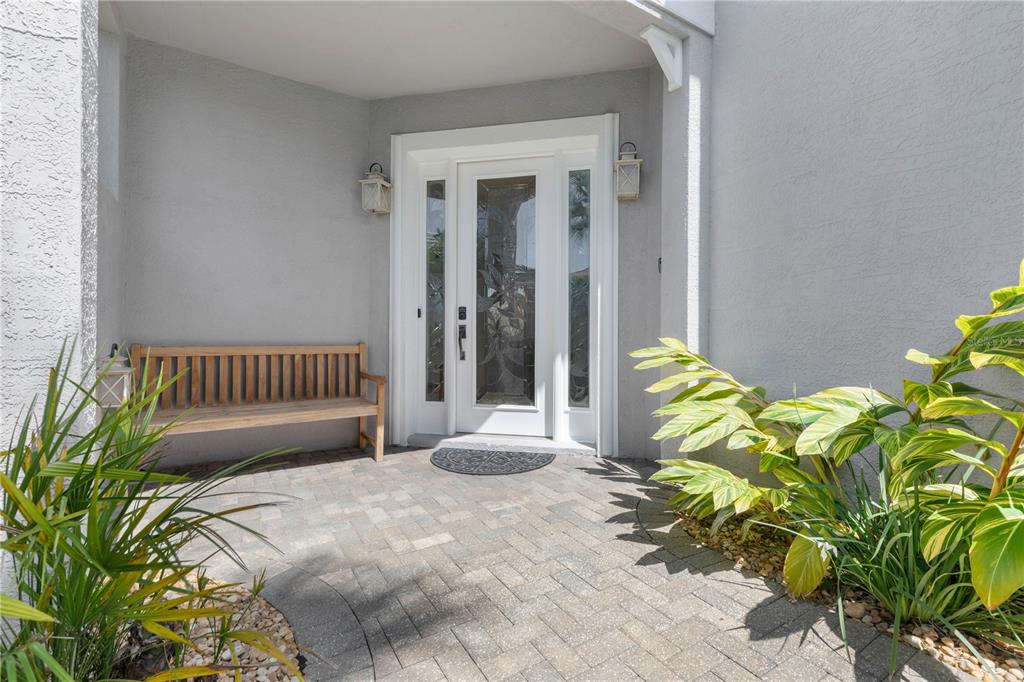 A front entryway features a wooden bench, a glass-paneled door, and a paved patio area — 12 CINNAMON BEACH WAY, PALM COAST, FL