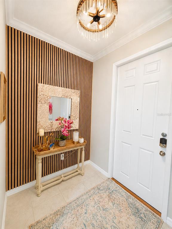 An entryway features a slatted wood accent wall, a console table, and a crystal chandelier — 31990 BLUE PASSING, WESLEY CHAPEL, FL