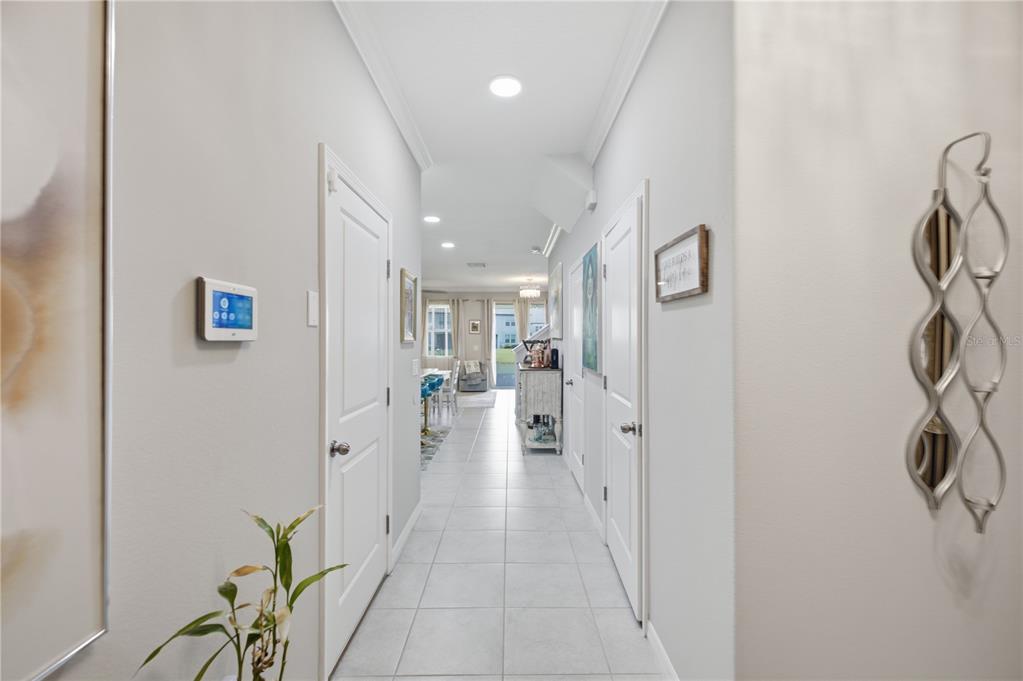 A bright hallway with white tile floors leads toward an open living area and kitchen — 31990 BLUE PASSING, WESLEY CHAPEL, FL