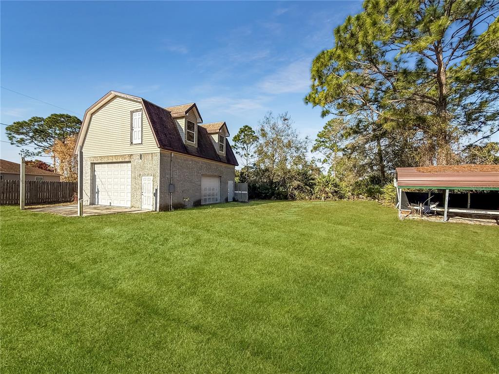A large two-story detached garage with a gambrel roof sits on a grassy lot — 1650 BURGUNDY STREET SE, PALM BAY, FL