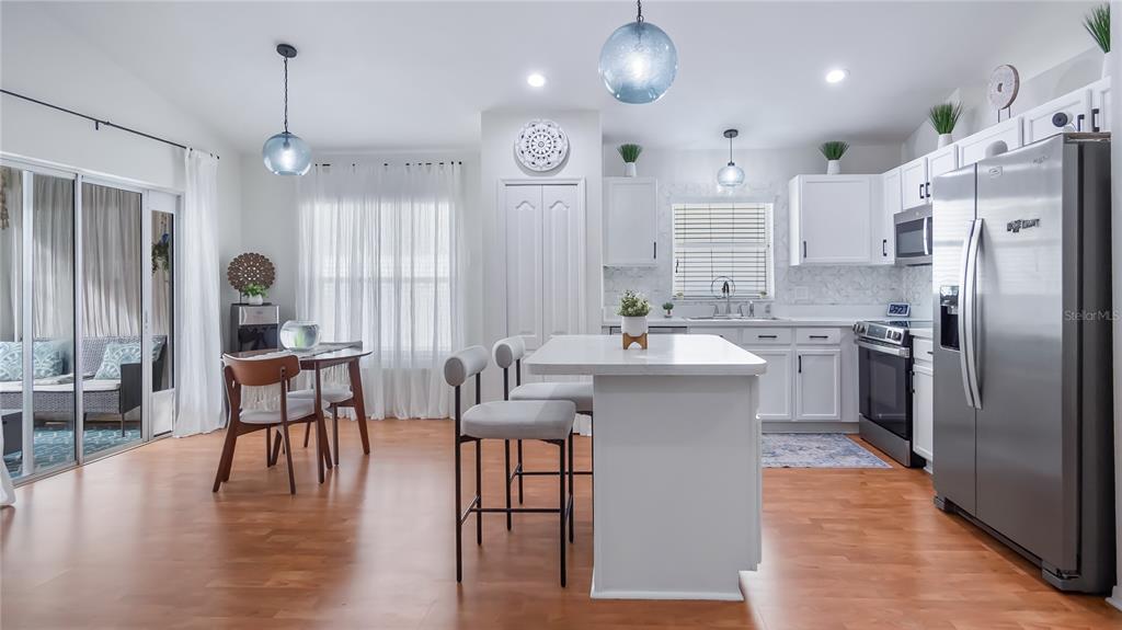 A kitchen and dining area features white cabinetry, a center island, and light wood flooring — 3931 ANDOVER CAY BOULEVARD, ORLANDO, FL