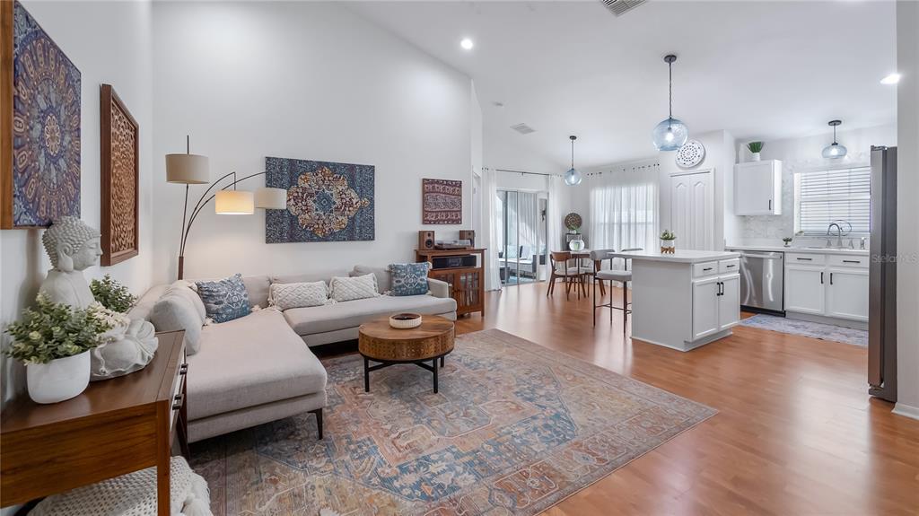 An open-concept living room and kitchen featuring a sectional sofa, area rug, and kitchen island — 3931 ANDOVER CAY BOULEVARD, ORLANDO, FL