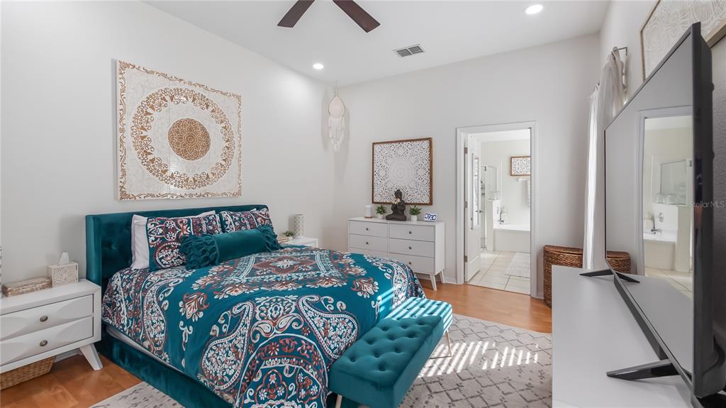 A bedroom features a teal upholstered bed, matching bench, white furniture, and a connected bathroom — 3931 ANDOVER CAY BOULEVARD, ORLANDO, FL