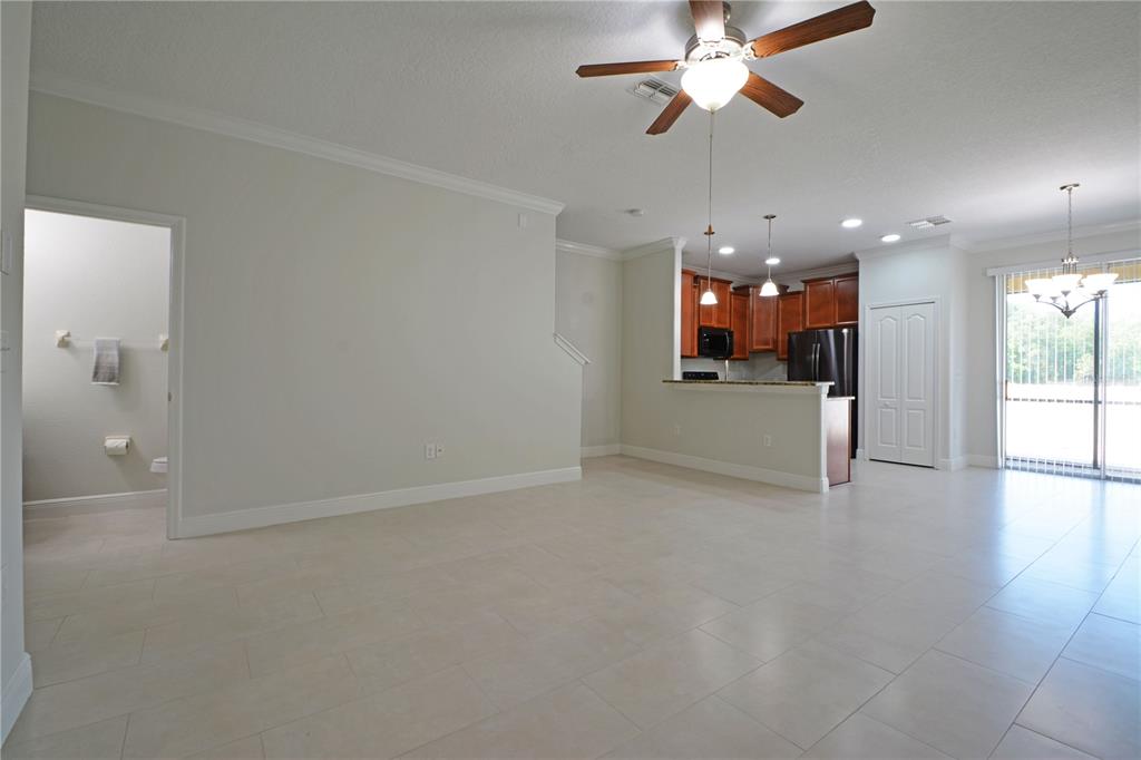 A long, empty room features light-colored tile flooring, a chandelier, and a white front door — 11925 GREENGATE DRIVE, HUDSON, FL