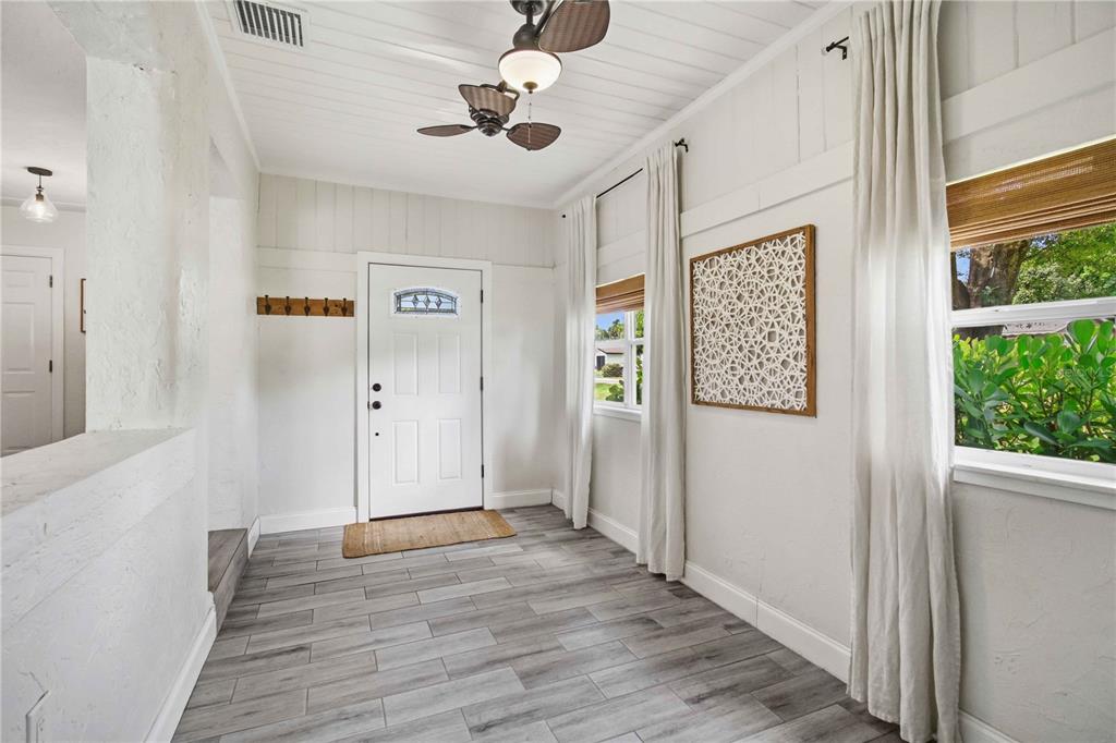 An entryway with wood-look tile flooring, white walls, a ceiling fan, and a front door — 2924 HILLVIEW STREET, SARASOTA, FL