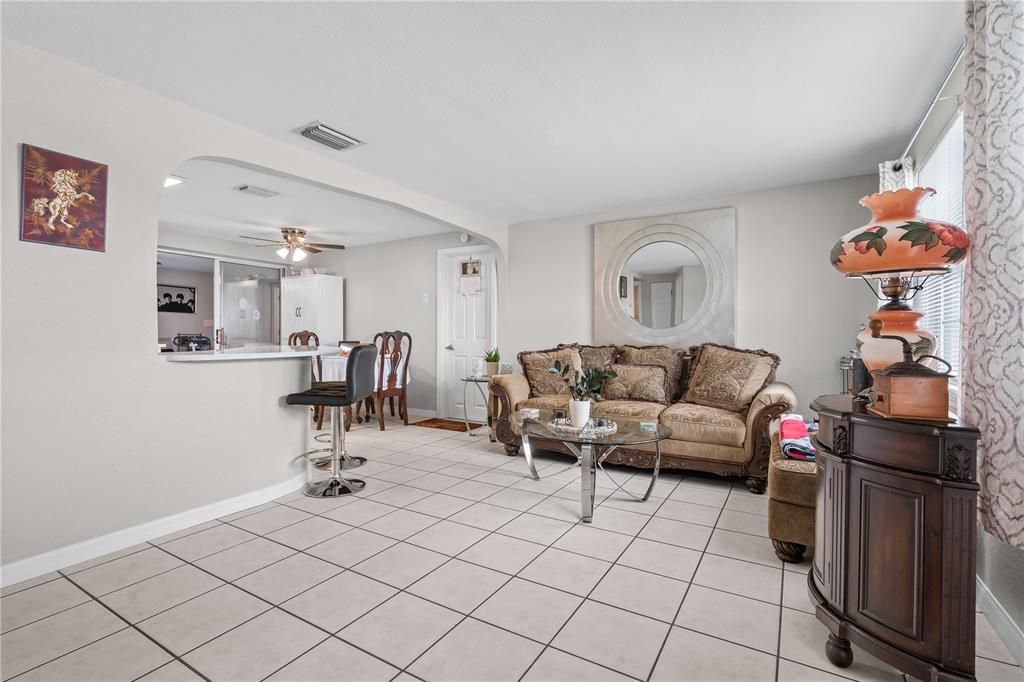 A living room with tile floors, a brown sofa, and a breakfast bar opening to a kitchen — 13323 NEPTUNE DRIVE, HUDSON, FL