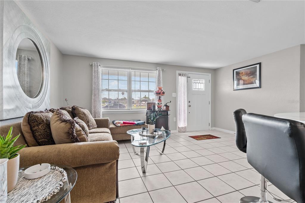 A living room features a beige sofa, a glass coffee table, and tile flooring — 13323 NEPTUNE DRIVE, HUDSON, FL