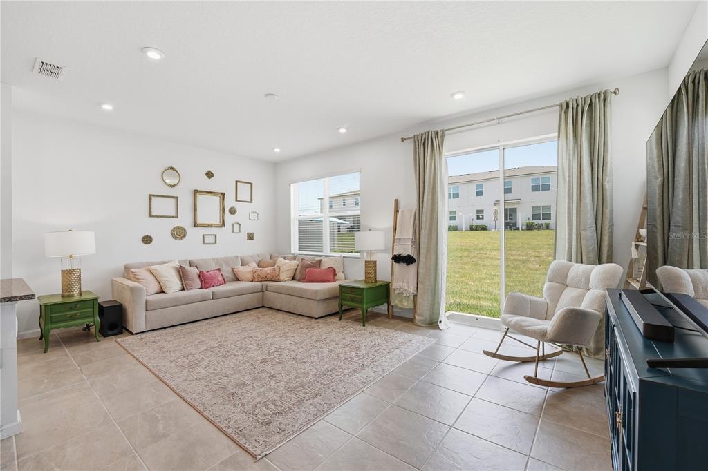 A living room features a sectional sofa, a rocking chair, and a sliding glass door — 1122 SEASIDE MIST TRAIL, KISSIMMEE, FL