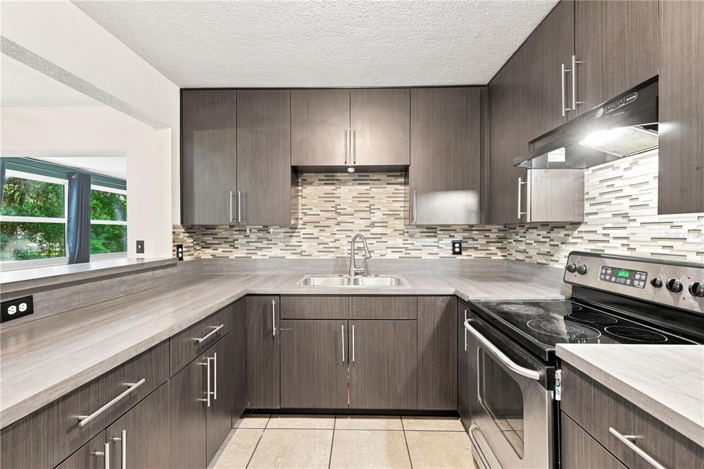 A kitchen with dark wood cabinets, a mosaic tile backsplash, and stainless steel appliances — 3410 CALUMET DRIVE, ORLANDO, FL