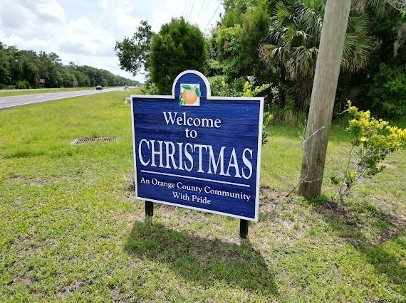 A blue welcome sign for the community of Christmas stands in a grassy field — 24502 E COLONIAL DRIVE, CHRISTMAS, FL