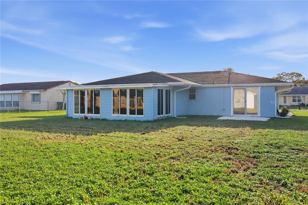 The exterior rear view of a light blue house with a large sunroom and lawn — 3634 LULLABY ROAD, NORTH PORT, FL