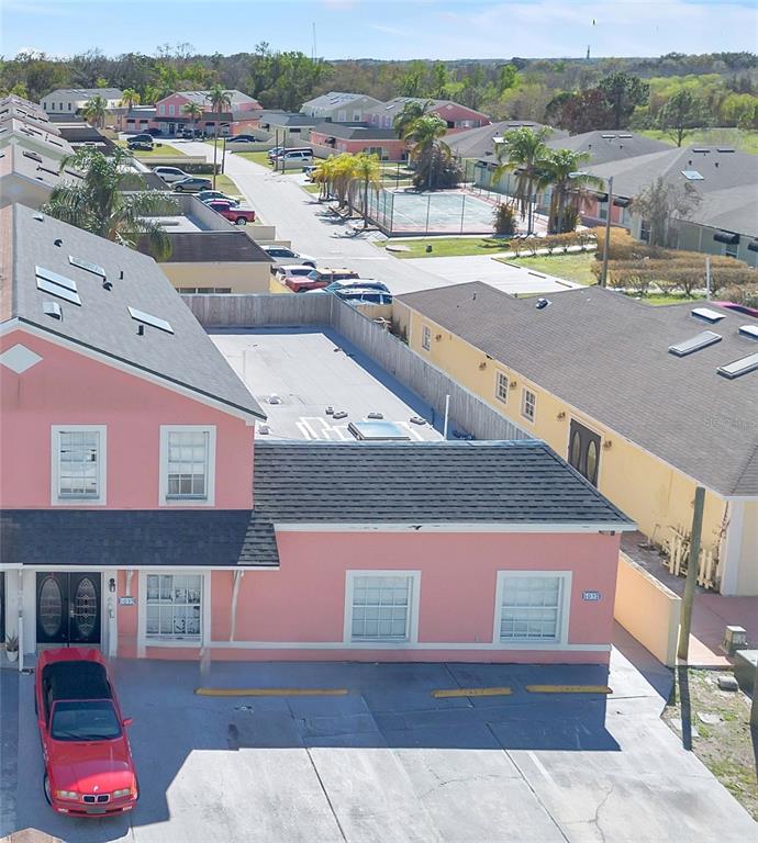 An aerial view shows a pink two-story building with a flat-roofed extension and parking — 1057 UNIVERSAL REST PLACE, KISSIMMEE, FL