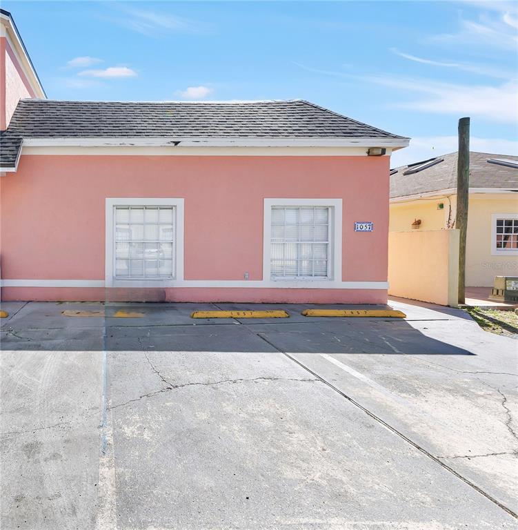 A pink exterior wall features two windows and parking spaces with yellow concrete bumpers — 1057 UNIVERSAL REST PLACE, KISSIMMEE, FL