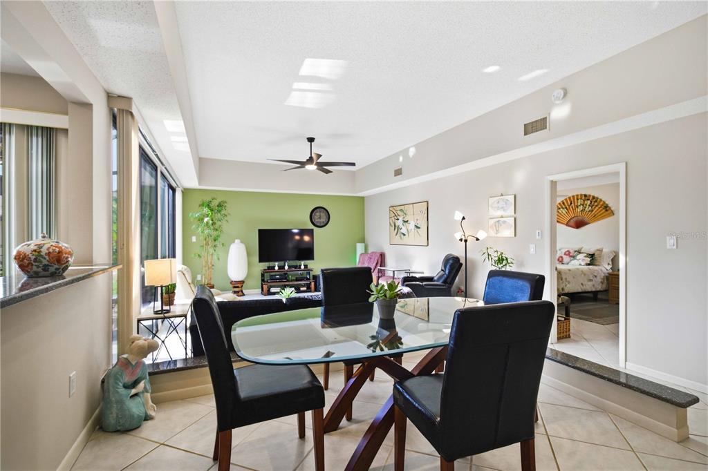 A dining area with a glass table and black chairs opens into a living room — 5257 MYRTLE WOOD UNIT 29, SARASOTA, FL