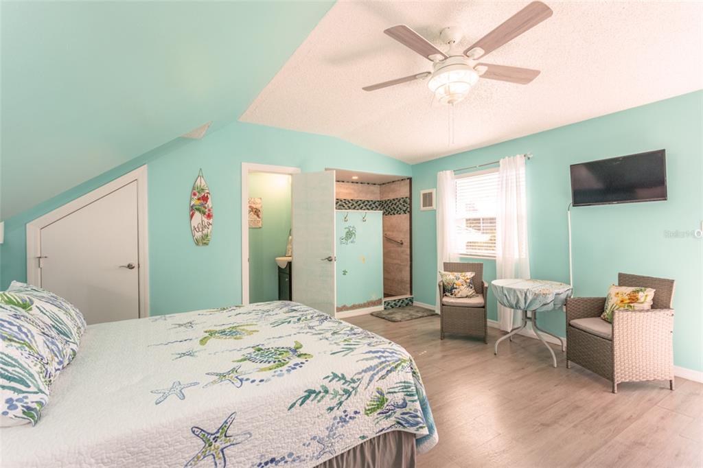 A living room with wood flooring, a ceiling fan, a television, and an adjacent kitchen — 44 FLAGLER DRIVE, PALM COAST, FL