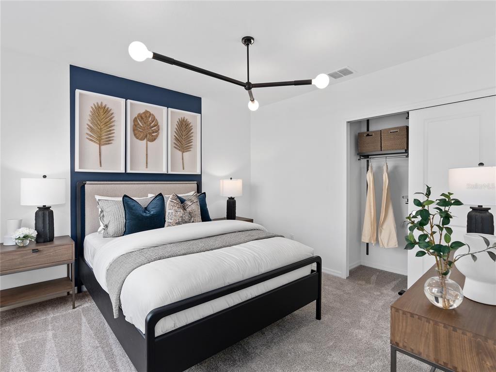 A bedroom features a navy accent wall, a black metal bed frame, and a modern chandelier — 10764 LEAFY LAUREL STREET, ORLANDO, FL