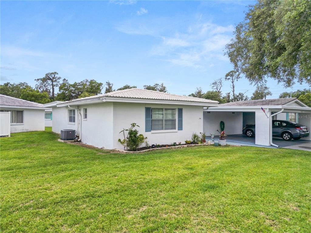 A white single-story house features a concrete driveway, a carport, and a green lawn — 711 BARBER CIRCLE UNIT 711, LAKELAND, FL