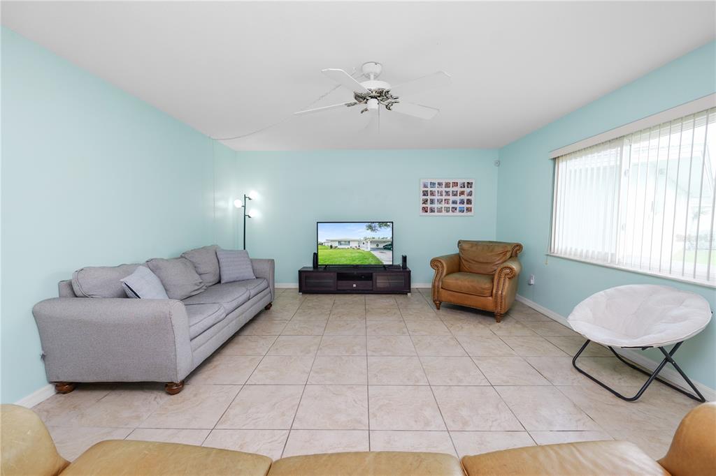 A living room with light blue walls, tile flooring, and tan leather furniture — 711 BARBER CIRCLE UNIT 711, LAKELAND, FL