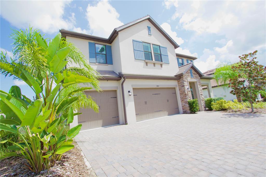 A two-story house with a beige stucco exterior, stone accents, and a paved driveway — 19825 CYPRESS BRIDGE DRIVE, ODESSA, FL
