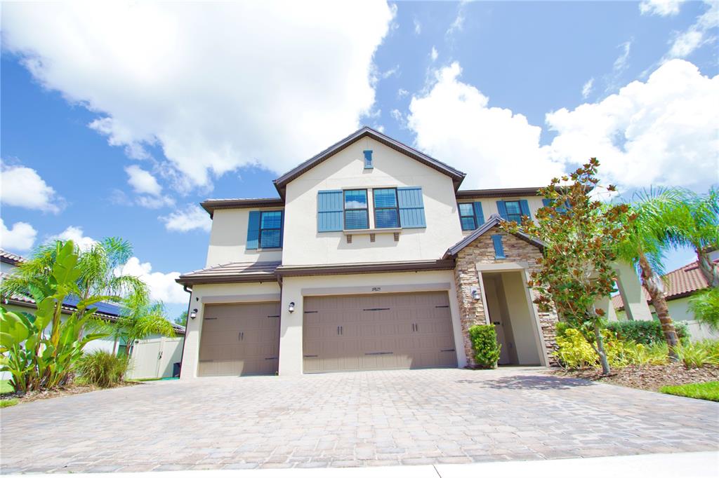 A two-story house with a beige stucco exterior, blue shutters, and a three-car garage — 19825 CYPRESS BRIDGE DRIVE, ODESSA, FL