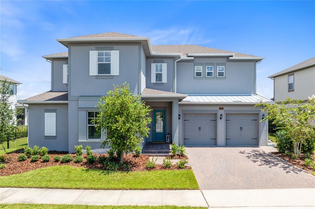 A two-story gray house with a teal front door and a two-car garage — 13439 MCMILLAN DRIVE, ORLANDO, FL