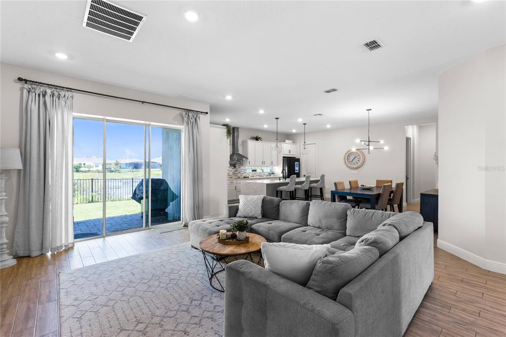 A living room with a gray sectional sofa opens to a kitchen and dining area — 13439 MCMILLAN DRIVE, ORLANDO, FL