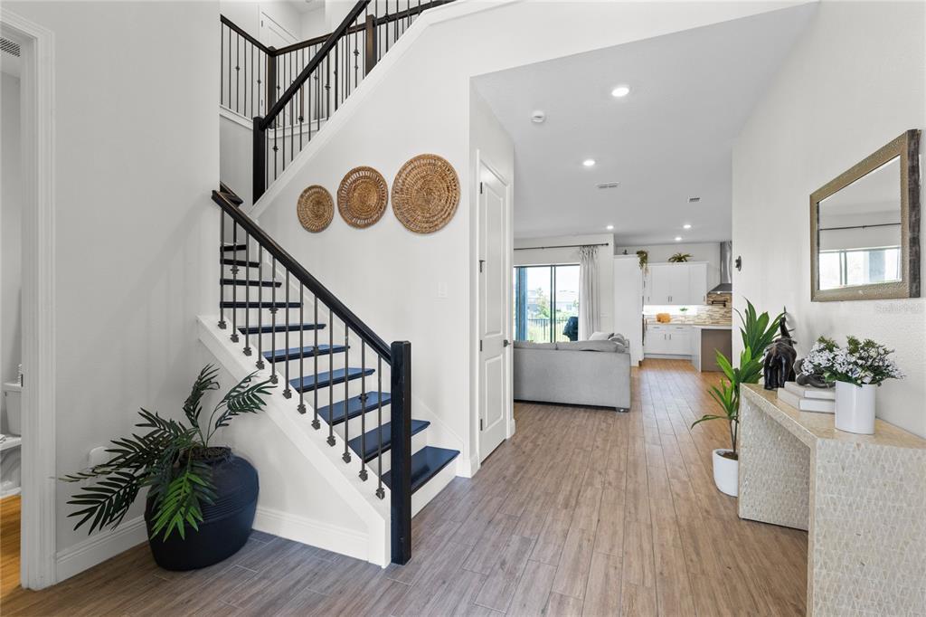 An entryway features a staircase with dark wood steps, a console table, and wall decor — 13439 MCMILLAN DRIVE, ORLANDO, FL