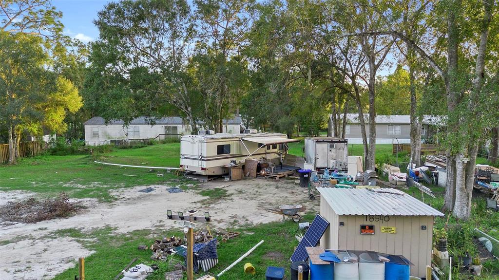 An outdoor view of a dirt lot featuring a parked RV, shed, and surrounding trees — 1ST AVENUE, ORLANDO, FL
