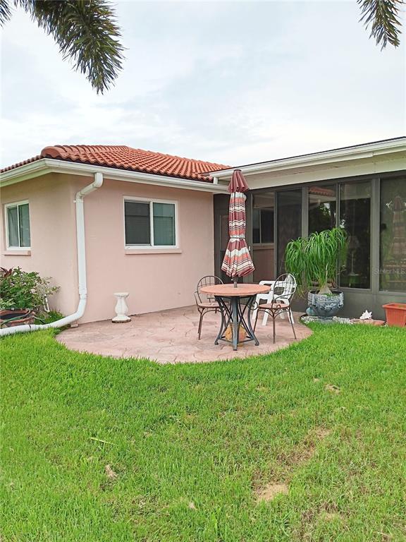 A pink house exterior features a small stone patio with a table, chairs, and umbrella — 980 N GONDOLA DRIVE, VENICE, FL