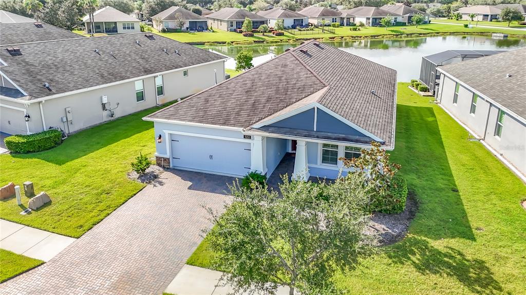 An aerial view shows a single-story house with a paved driveway and a backyard pond — 5252 CAPPLEMAN LOOP, BROOKSVILLE, FL